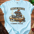 Light blue t-shirt with a grumpy black cat wearing a witch hat, "HOCUS POCUS" and "I CANNOT FOCUS" text.