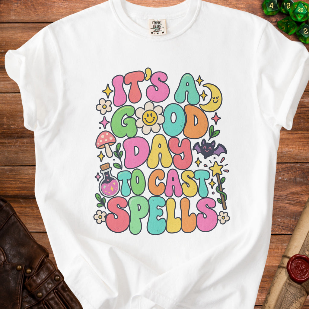 White t-shirt with "It's a good day to cast spells" text and whimsical graphics.