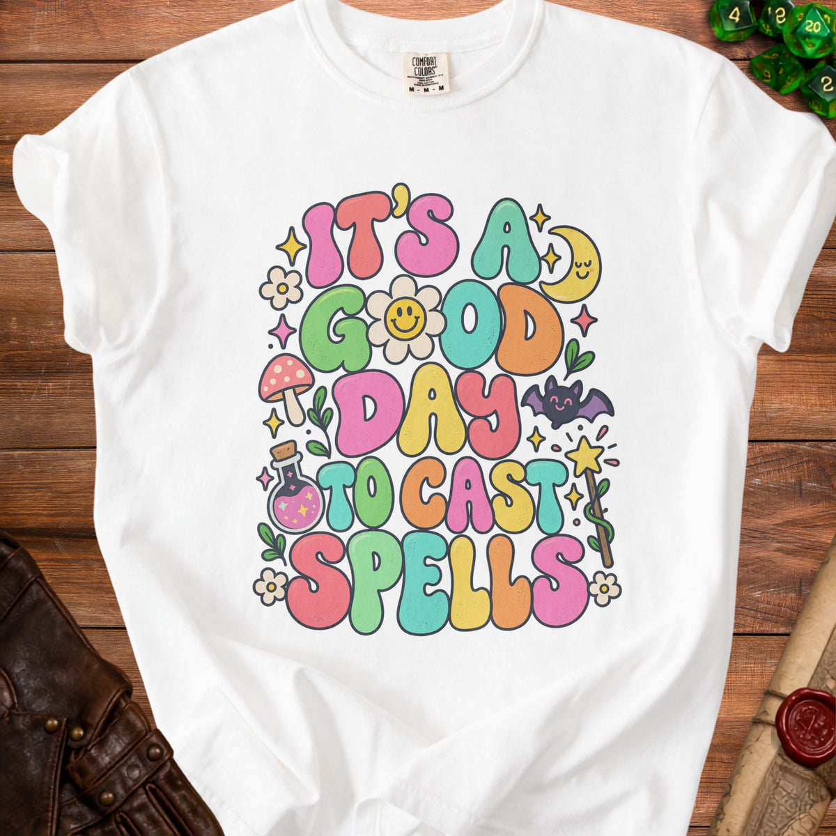White t-shirt with "It's a good day to cast spells" text and whimsical graphics.
