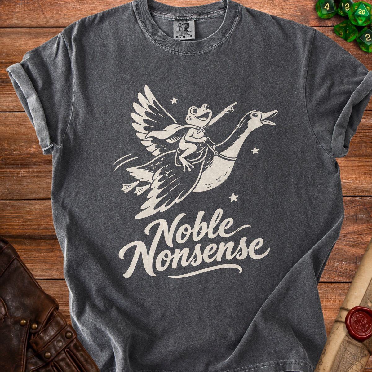 Dark grey t-shirt with a cream graphic of a frog flying on a goose, captioned "Noble Nonsense".