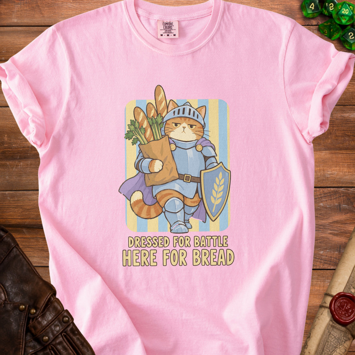 Pink t-shirt with knight cat graphic holding bread, text reads "DRESSED FOR BATTLE HERE FOR BREAD."