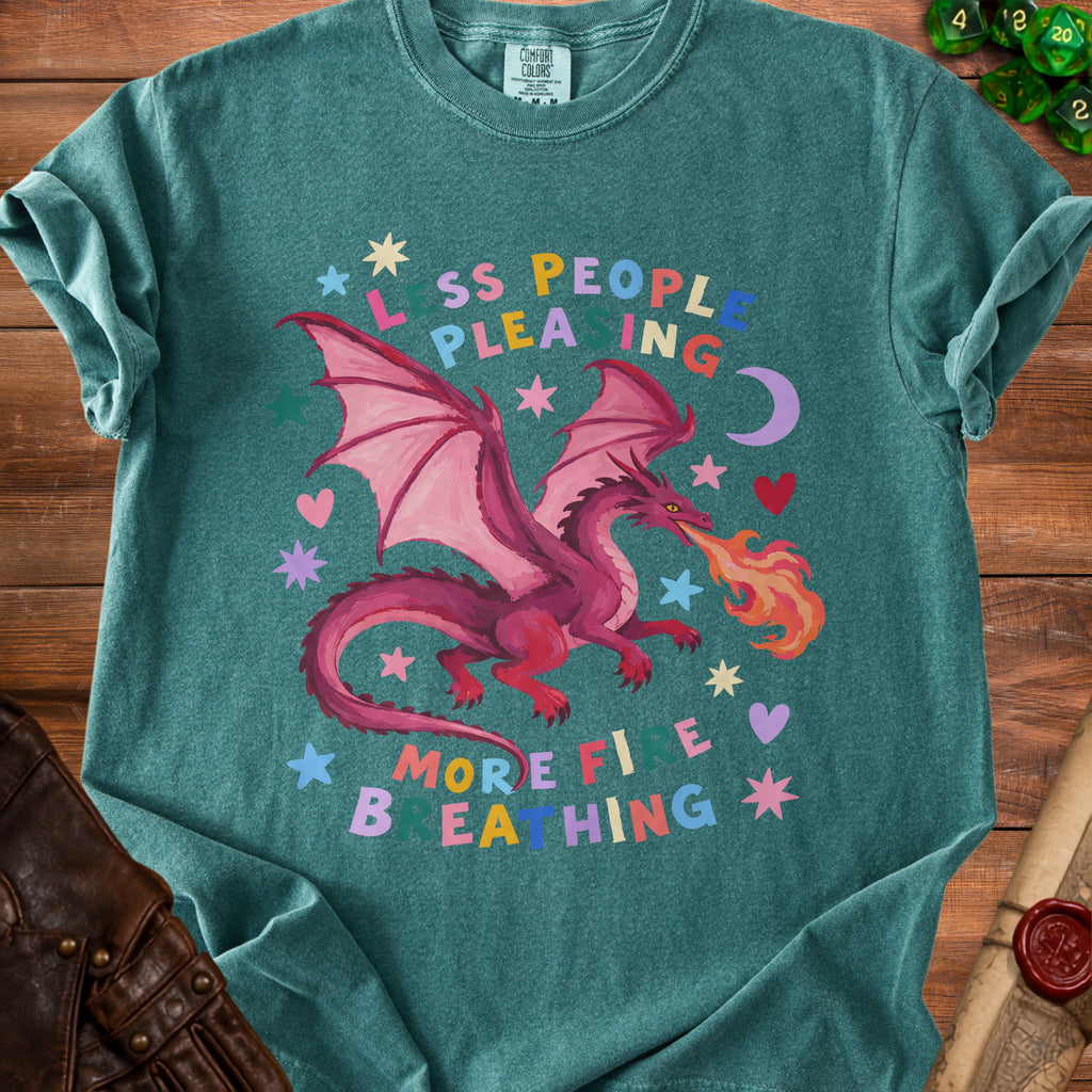 Teal t-shirt with pink dragon breathing fire, stars, hearts, and the words "Less People Pleasing More Fire Breathing".