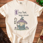 Cream t-shirt with "Tiny hat, huge stress" graphic featuring a mushroom wizard.
