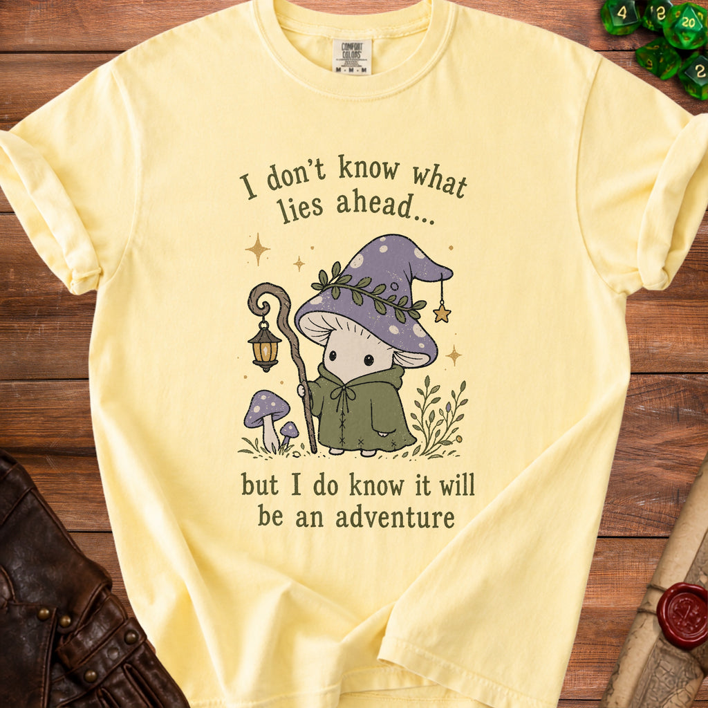Light yellow t-shirt with a graphic of a mushroom adventurer and the text "I don't know what lies ahead... but I do know it will be an adventure".