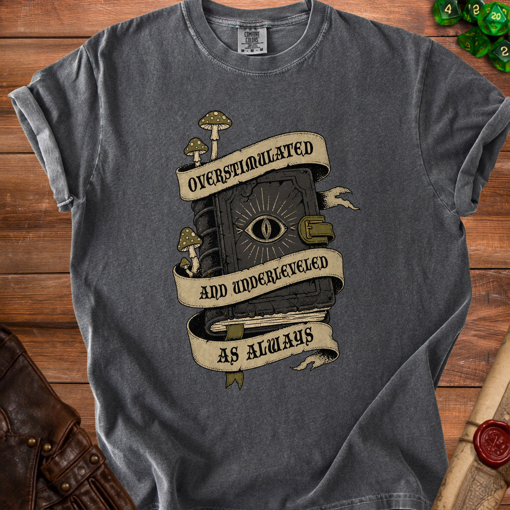 Dark gray t-shirt with a graphic of a book with an eye, mushrooms, and banners reading "Overstimulated and Underleveled as Always".
