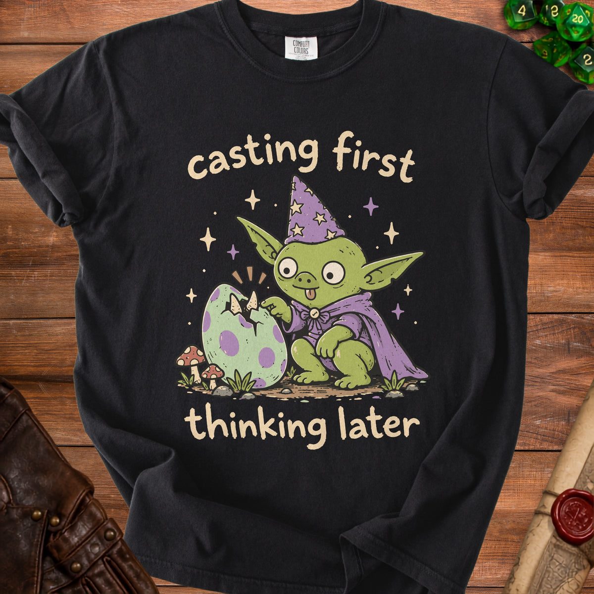 Black t-shirt with a goblin hatching an egg, text "casting first thinking later".