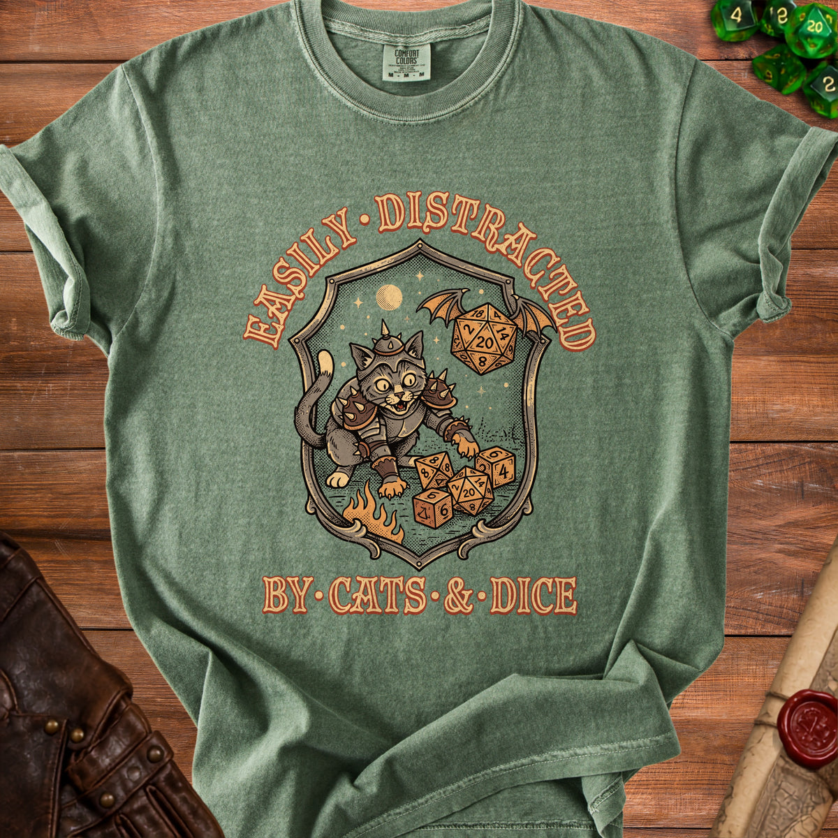 Green t-shirt with shield graphic: cat in armor, dice, moon, text "Easily Distracted by Cats & Dice".