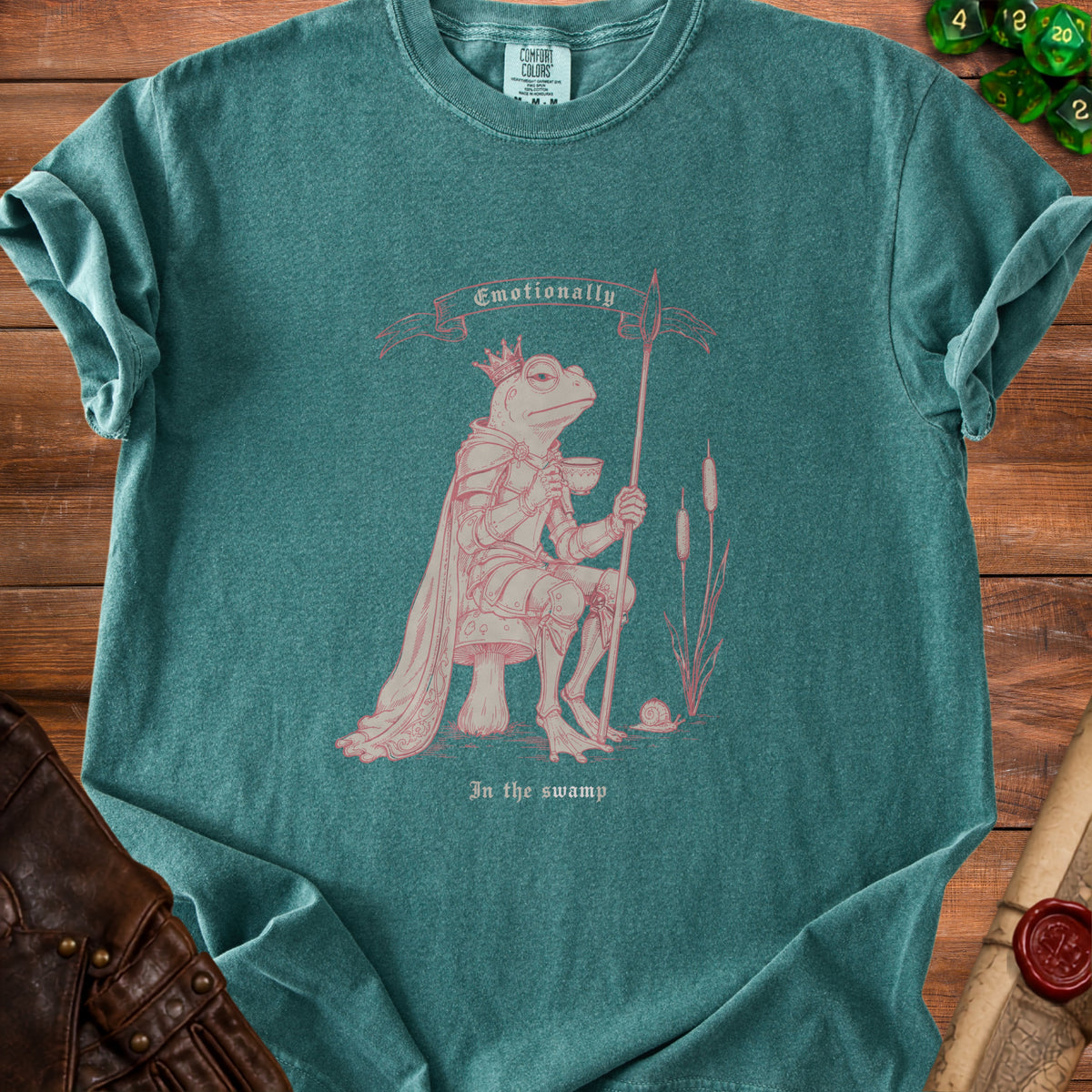 Green t-shirt with pink print of a crowned frog in armor holding a cup and spear.