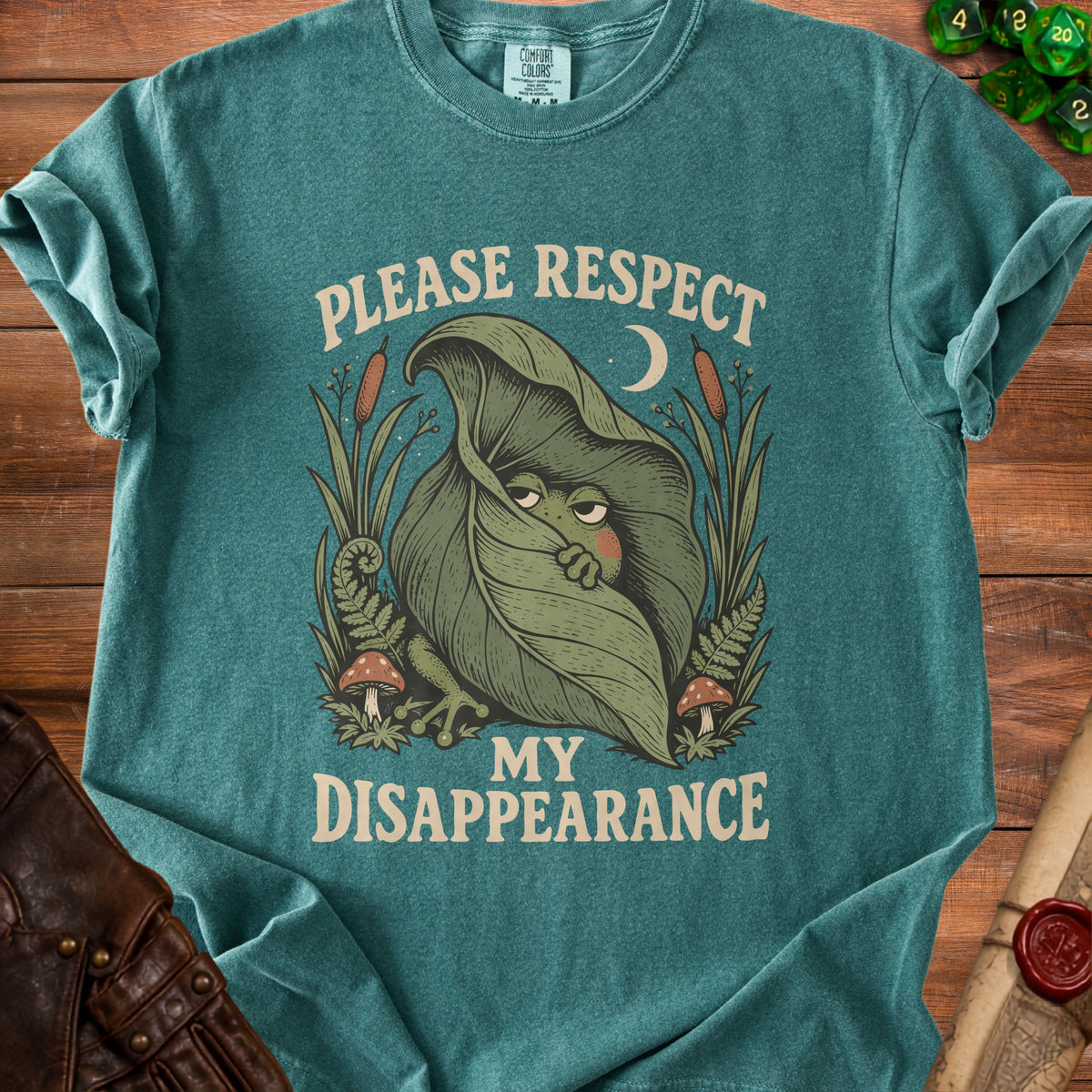 Green t-shirt with "Please Respect My Disappearance" text and a shy frog hiding under a leaf.