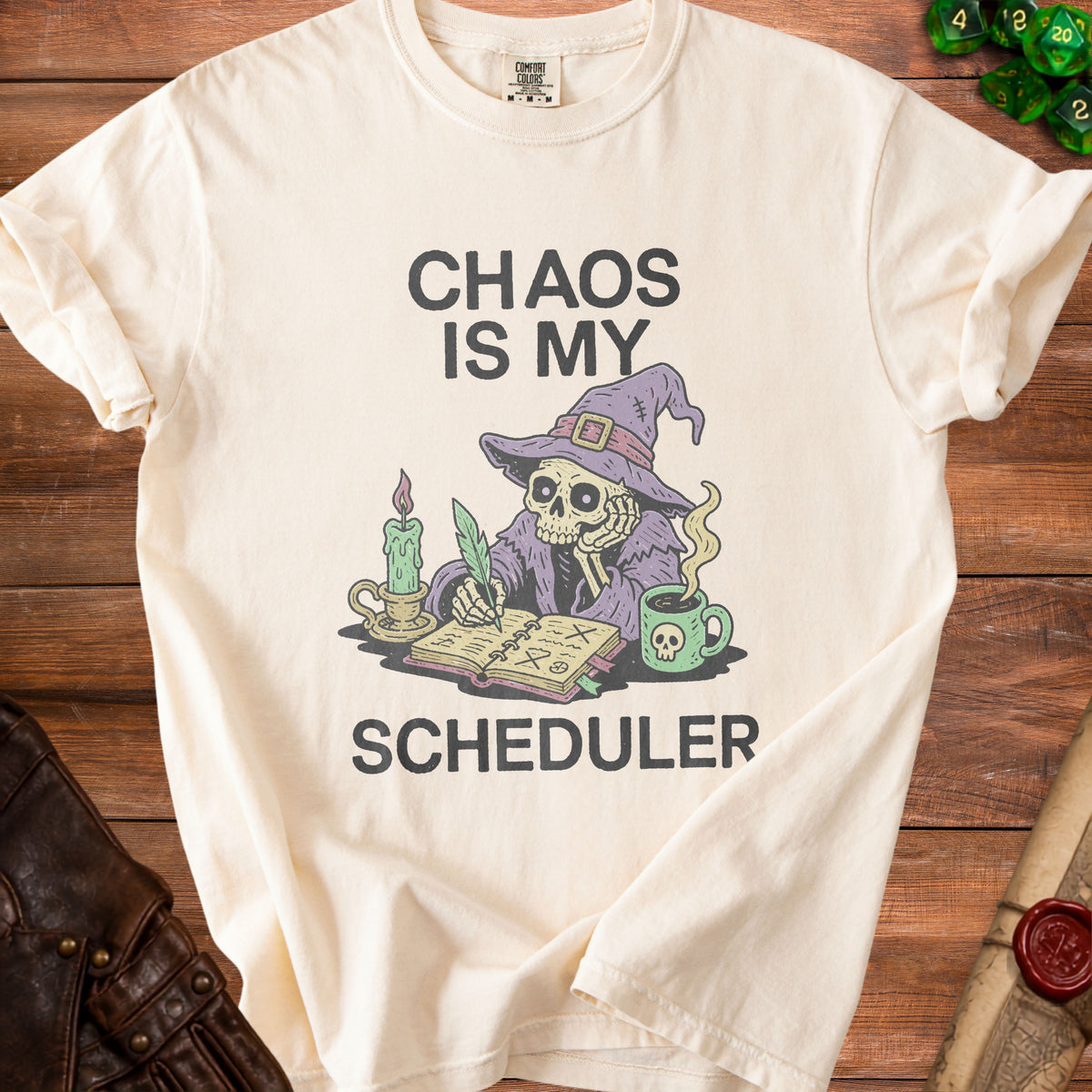 Cream t-shirt with "Chaos Is My Scheduler" text and skeleton wizard illustration.