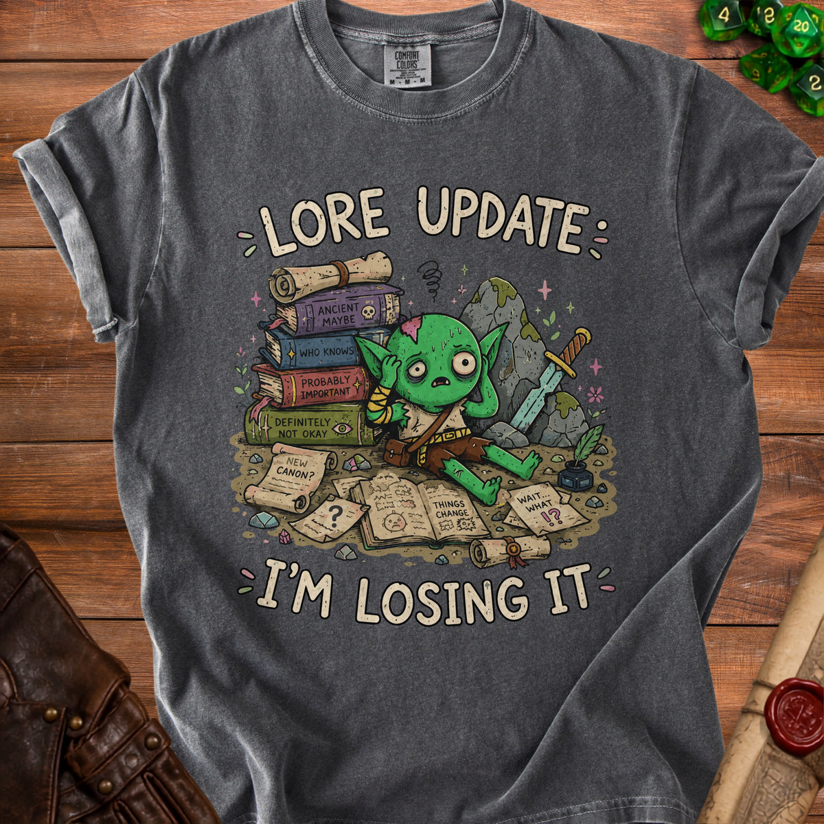 T-shirt with a distressed graphic of a green goblin surrounded by books and scrolls, reading "Lore Update: I'm Losing It".