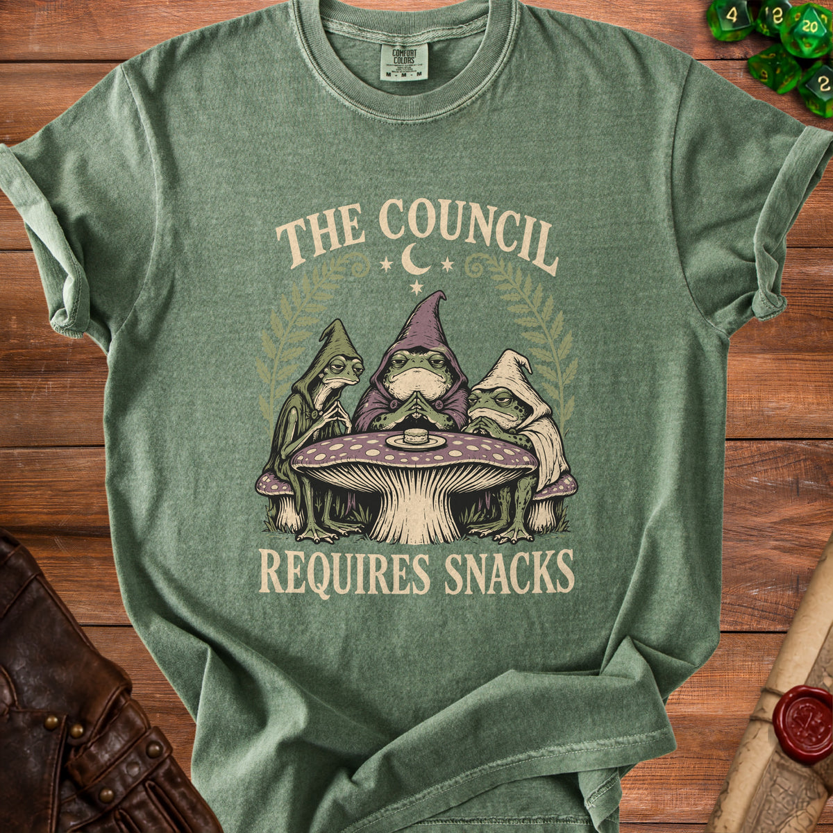 Green t-shirt with a toad council on a mushroom table, reading "The Council Requires Snacks".