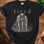 Black t-shirt with "tired" text above a seated knight holding a sword.