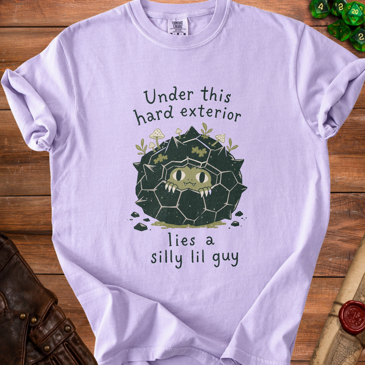Light purple t-shirt with green text and illustration of a rock creature.