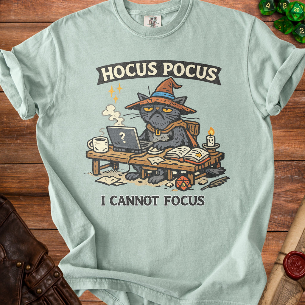 Light blue t-shirt with a grumpy cat wearing a witch hat and cape, typing on a laptop, with text "Hocus Pocus I Cannot Focus."