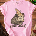 Pink t-shirt with opossum wearing wizard hat and "ARCANE ADJACENT" text.