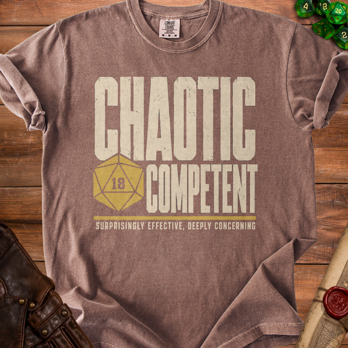 Brown t-shirt with "Chaotic Competent" and "Surprisingly Effective, Deeply Concerning" text.
