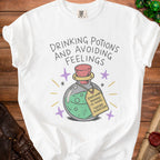 White t-shirt with text "Drinking Potions and Avoiding Feelings" and a potion bottle.