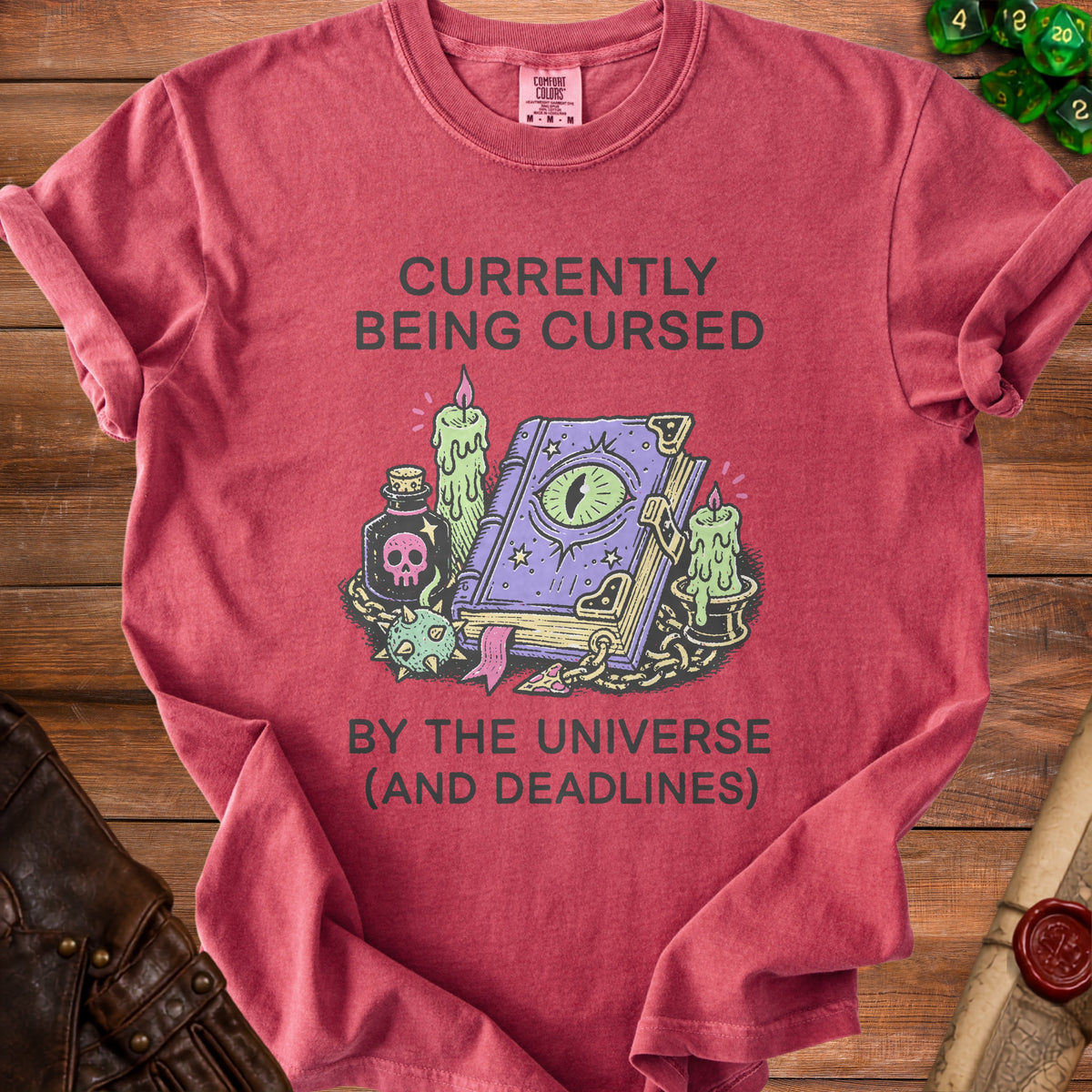 T-shirt with "Currently Being Cursed By The Universe (And Deadlines)" text and mystical graphics.