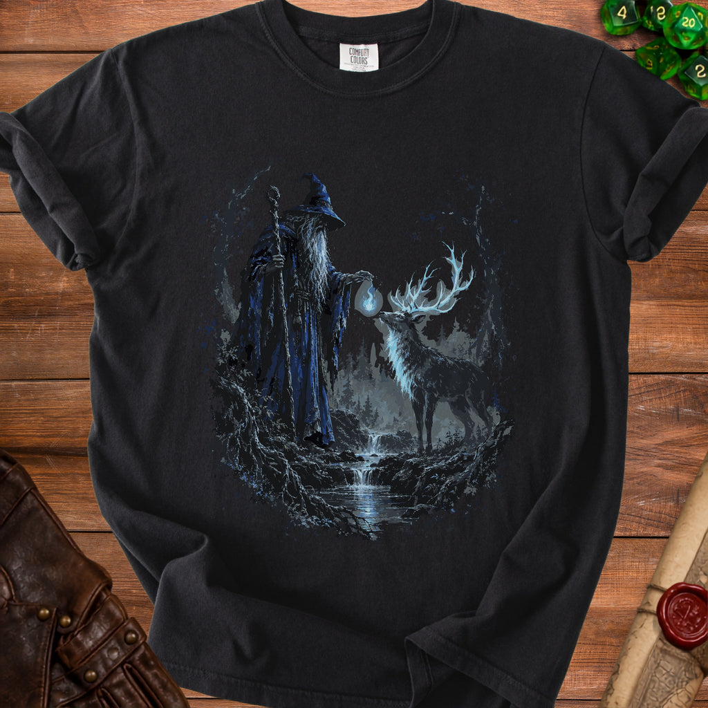 Wizard and glowing deer in a forest stream scene on a black t-shirt.