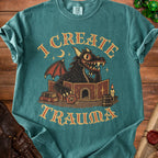 A teal t-shirt featuring a cartoon dragon DM behind a screen, with text reading I CREATE TRAUMA.
