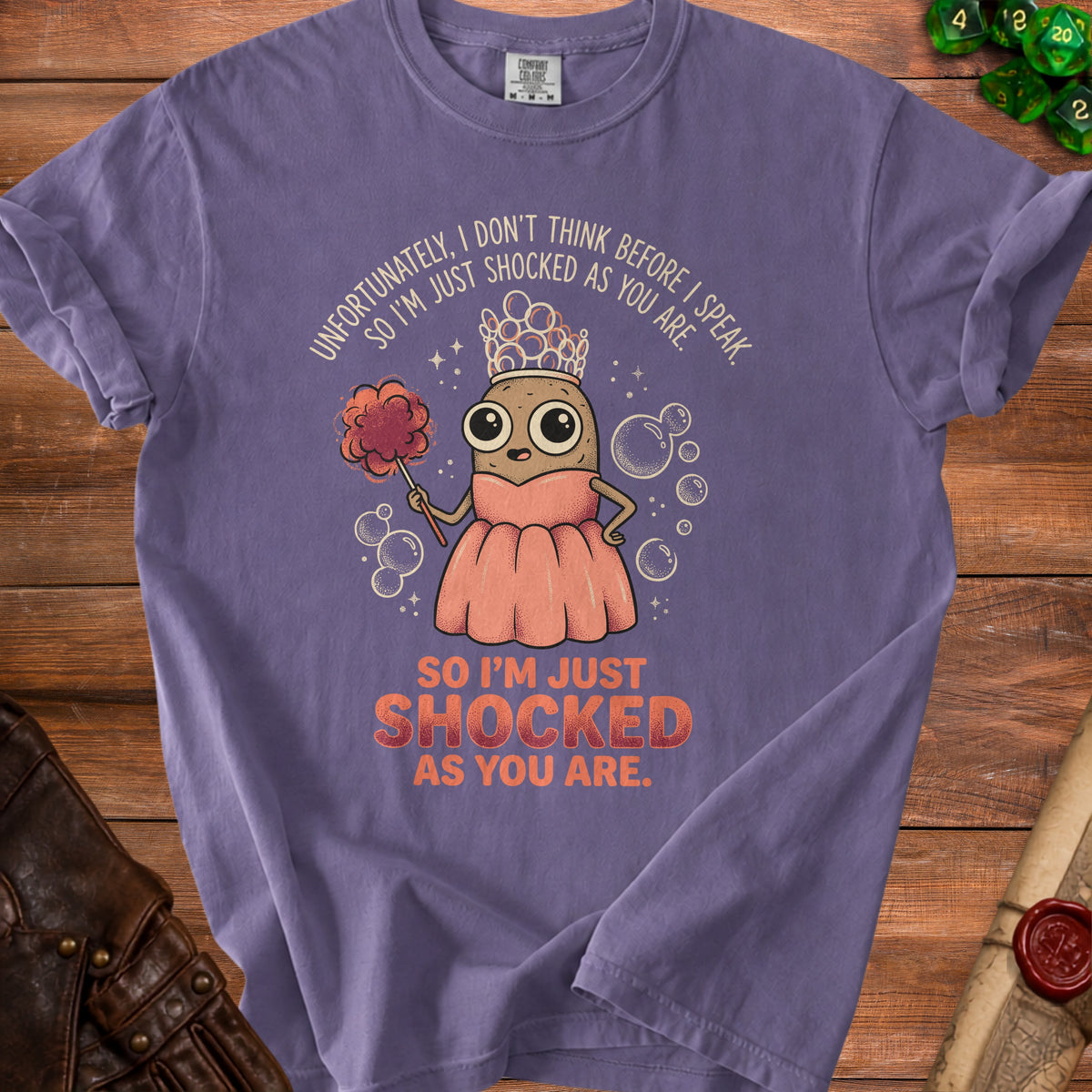 Purple t-shirt with cartoon potato wearing crown and holding poof, text reads "SO I'M JUST SHOCKED AS YOU ARE."