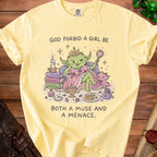 Yellow t-shirt with "God forbid a girl be both a muse and a menace" text and goblin queen graphic.