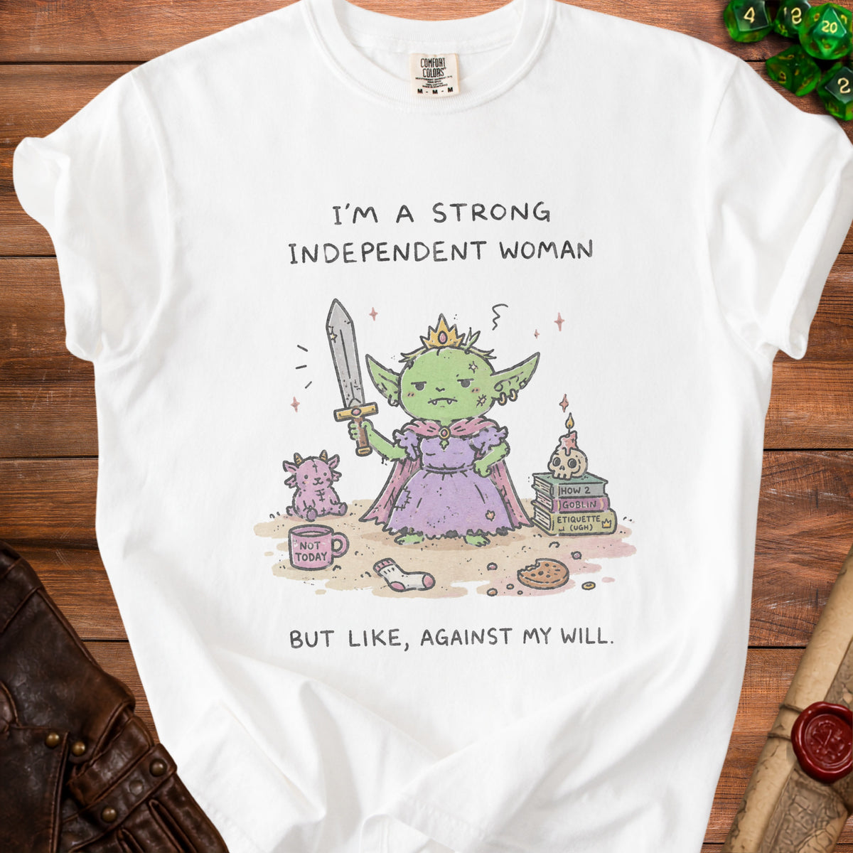 White t-shirt with "I'm a strong independent woman, but like, against my will" text and goblin illustration.