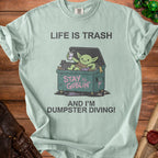 Light blue t-shirt with "Life is Trash" and a goblin in a dumpster.