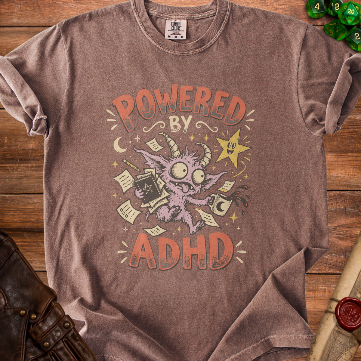 T-shirt with "Powered By ADHD" text and cartoon monster holding books and coffee.