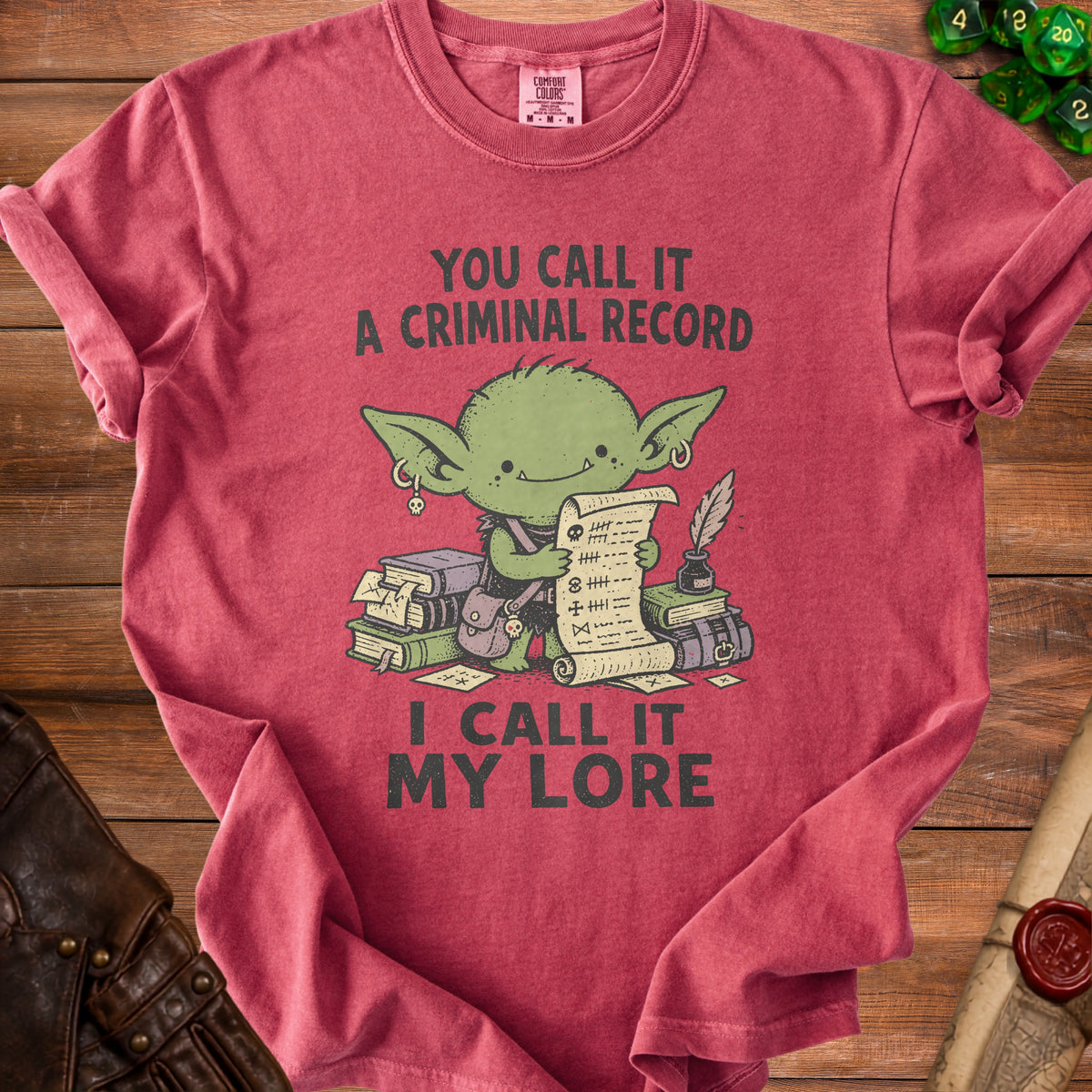 Crimson t-shirt with a green goblin character holding a scroll. Text reads "You Call It A Criminal Record, I Call It My Lore".