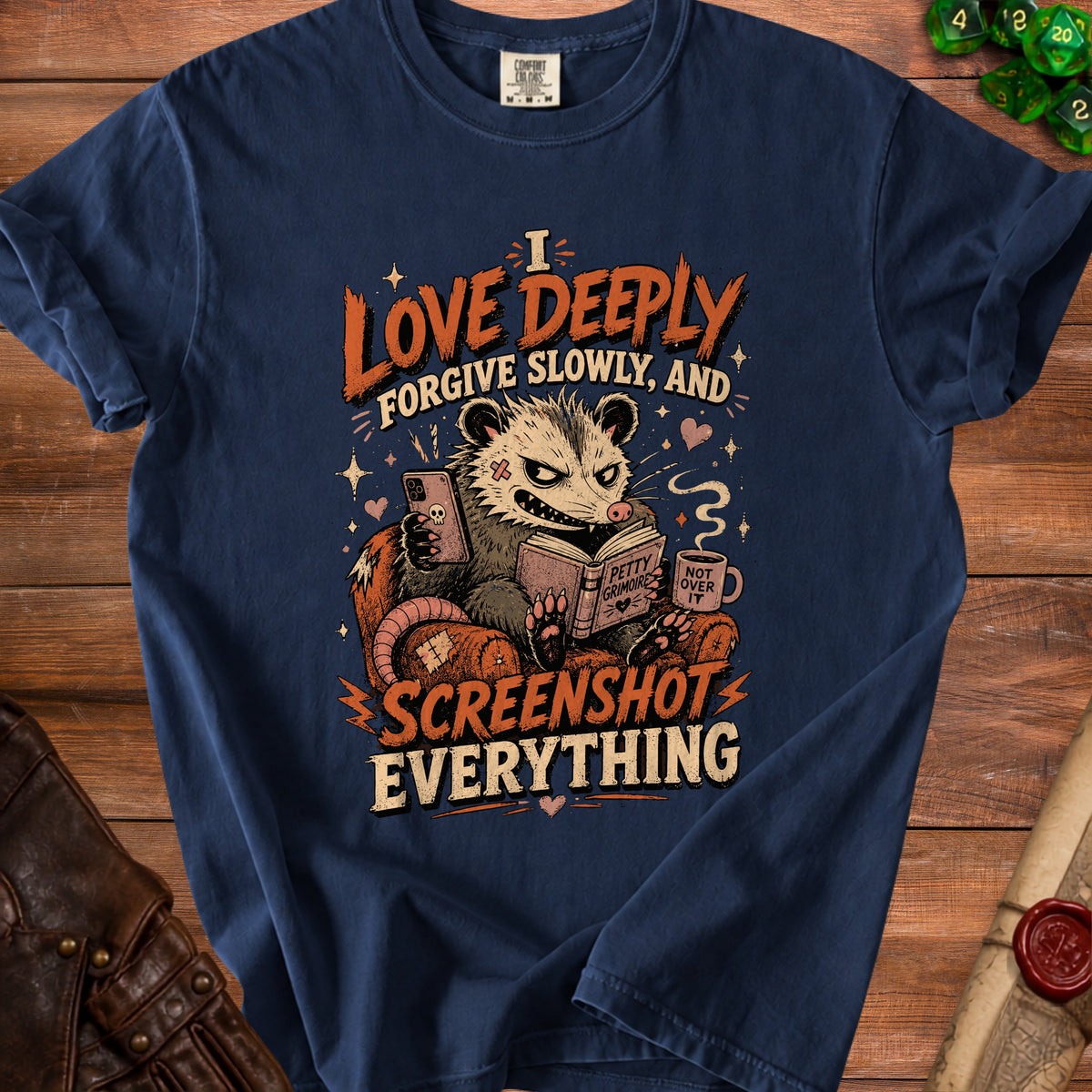 Navy blue t-shirt with a possum reading a book and holding a phone, text reads "I LOVE DEEPLY FORGIVE SLOWLY, AND SCREENSHOT EVERYTHING".