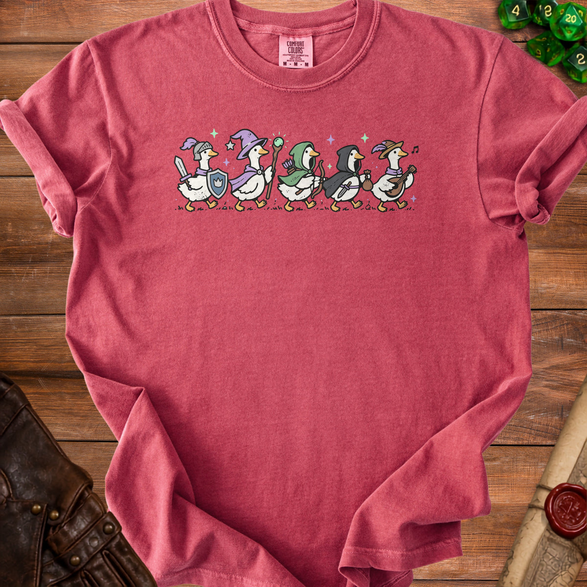 Six cartoon ducks dressed as fantasy adventurers walking in a line on a t-shirt.