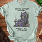T-shirt graphic: skeleton wizard sitting in a chair, "Social Battery Drained. Please Cast Left Alone."