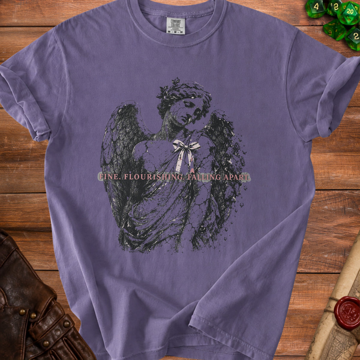 Purple t-shirt with a cracked angel graphic and text "FINE. FLOURISHING. FALLING APART."