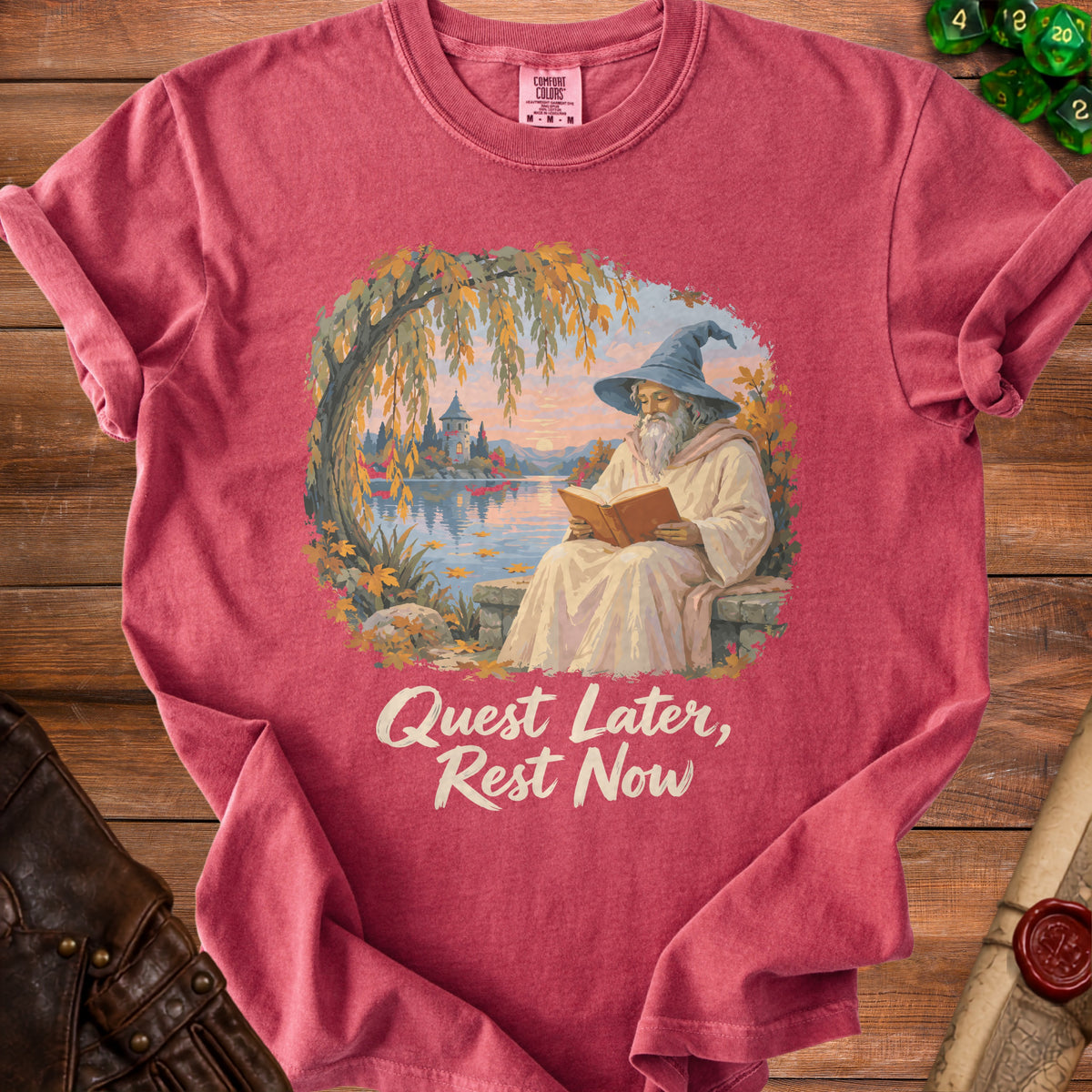 T-shirt with illustration of wizard reading by a lake with text "Quest Later, Rest Now".