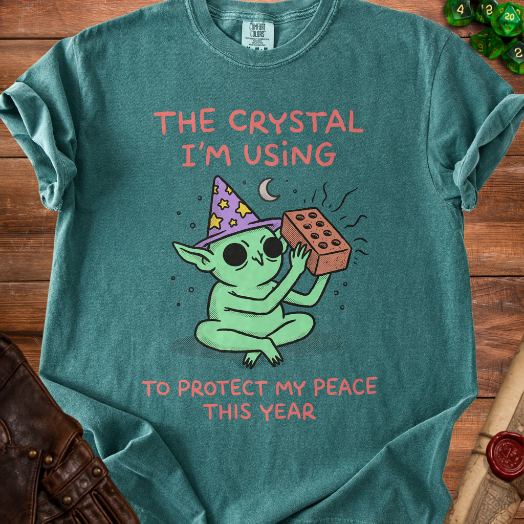 Green t-shirt with a goblin holding a brick and the text "The crystal I'm using to protect my peace this year".