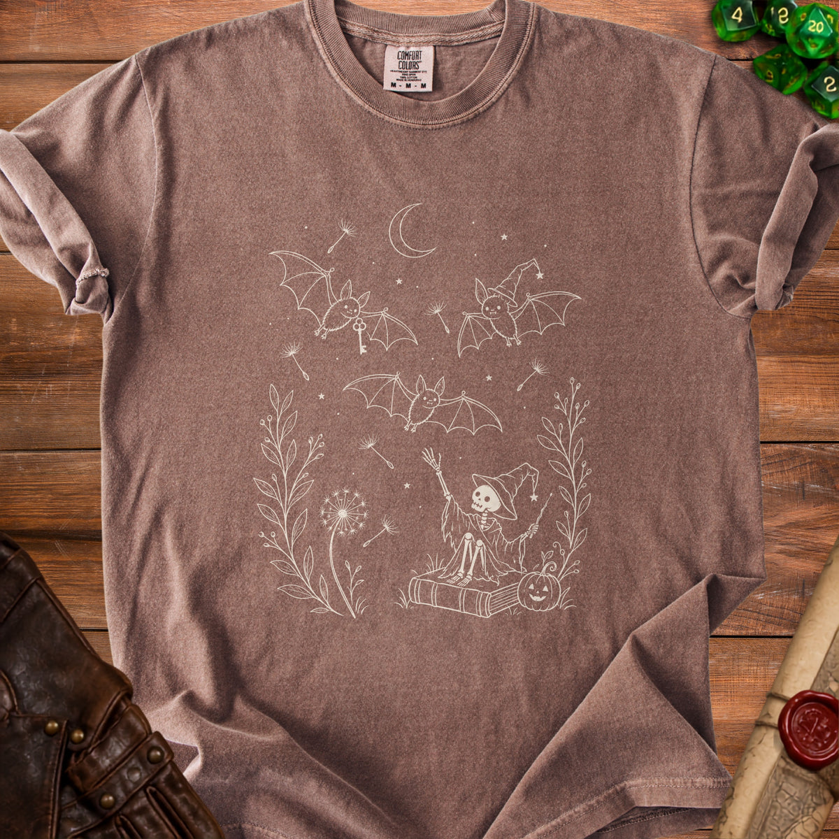 Brown t-shirt with white line drawing of bats, skeleton wizard, moon, and Halloween elements.