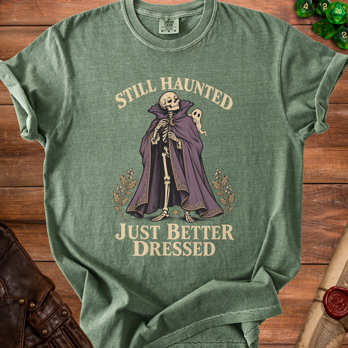 Green t-shirt with skeleton graphic and text "STILL HAUNTED JUST BETTER DRESSED".