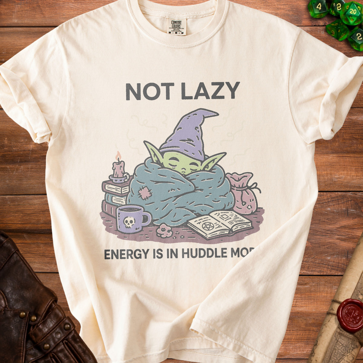 Cream t-shirt with "NOT LAZY ENERGY IS IN HUDDLE MO" and cartoon goblin graphic.