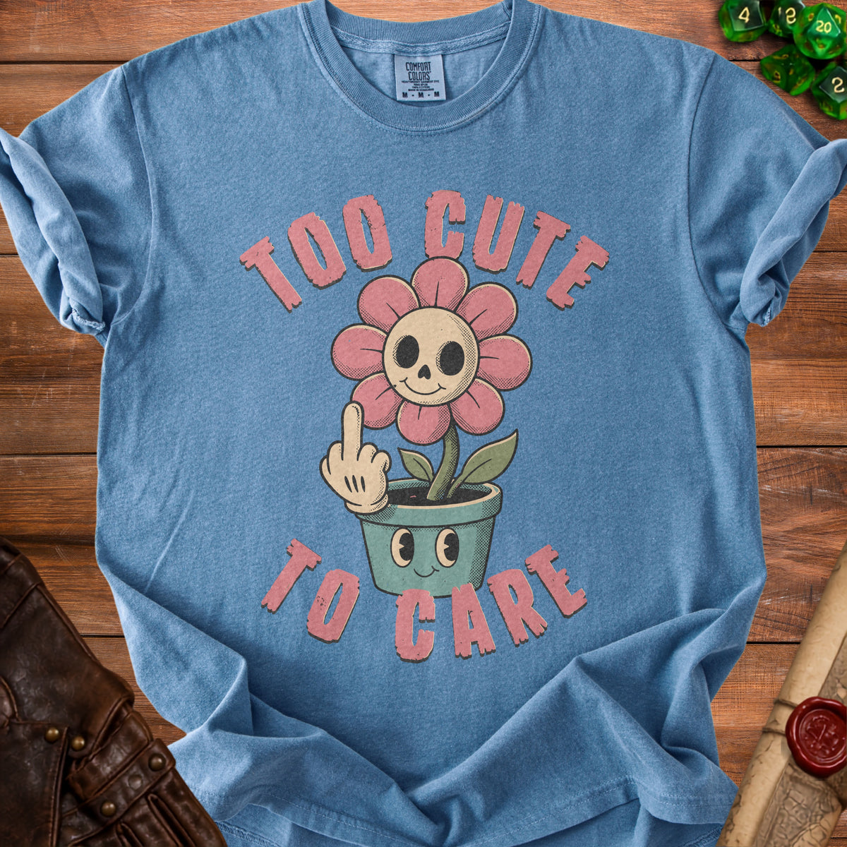 Blue t-shirt with "TOO CUTE TO CARE" and skull flower graphic.