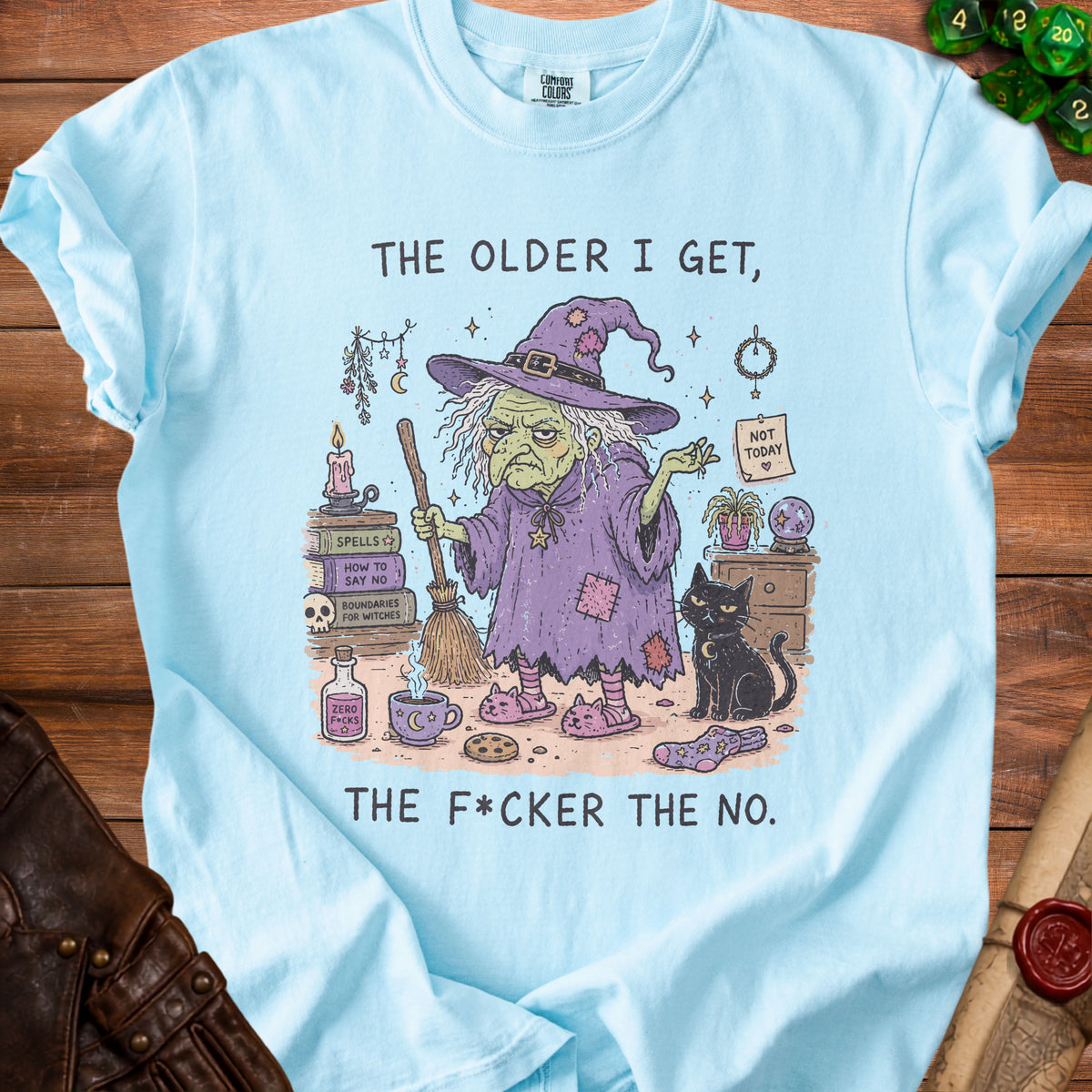 Light blue t-shirt with illustration of a witch and cat, reads "The older I get, the f*cker the no."