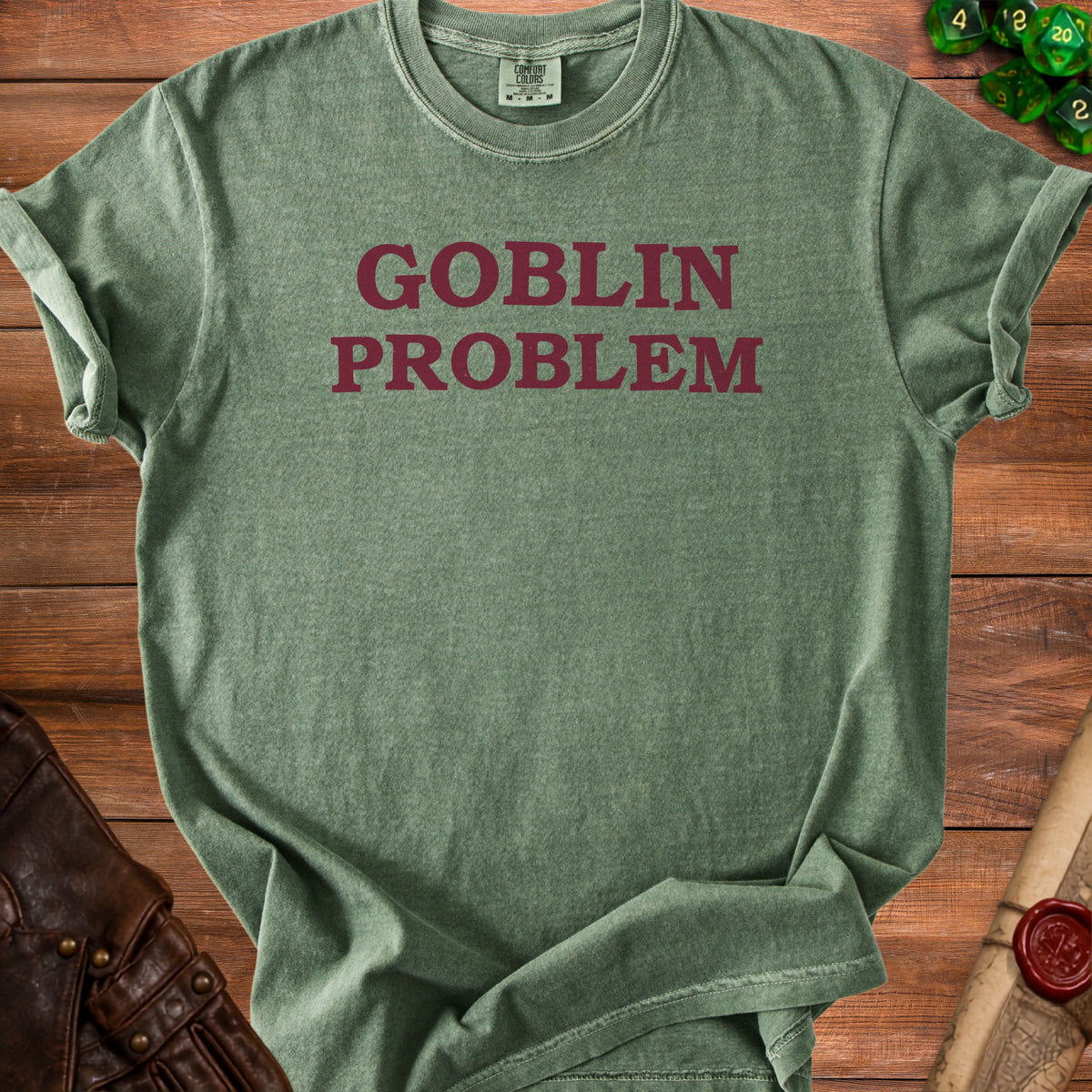 Green t-shirt with "GOBLIN PROBLEM" text, dice, and leather accessories.