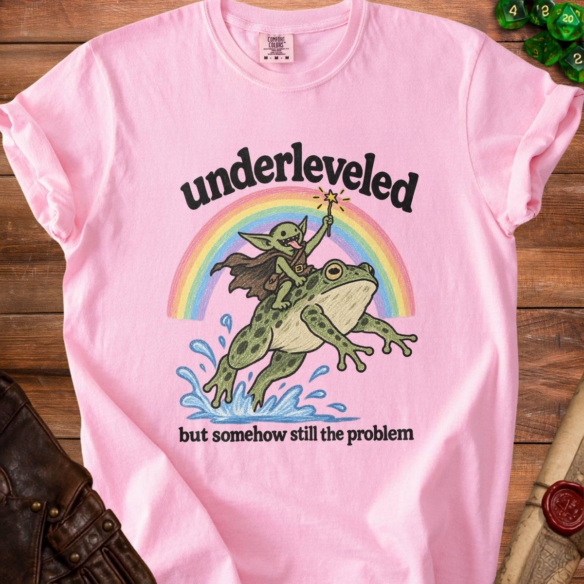 Pink t-shirt with "underleveled but somehow still the problem" and a goblin riding a frog.