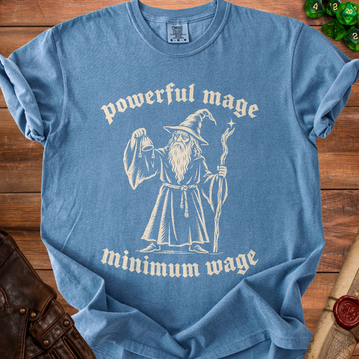 Blue t-shirt with graphic of a wizard holding a pouch and staff with text "powerful mage minimum wage".