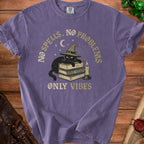 Purple t-shirt with a black cat wearing a witch hat on books, text reads "NO SPELLS. NO PROBLEMS. ONLY VIBES."
