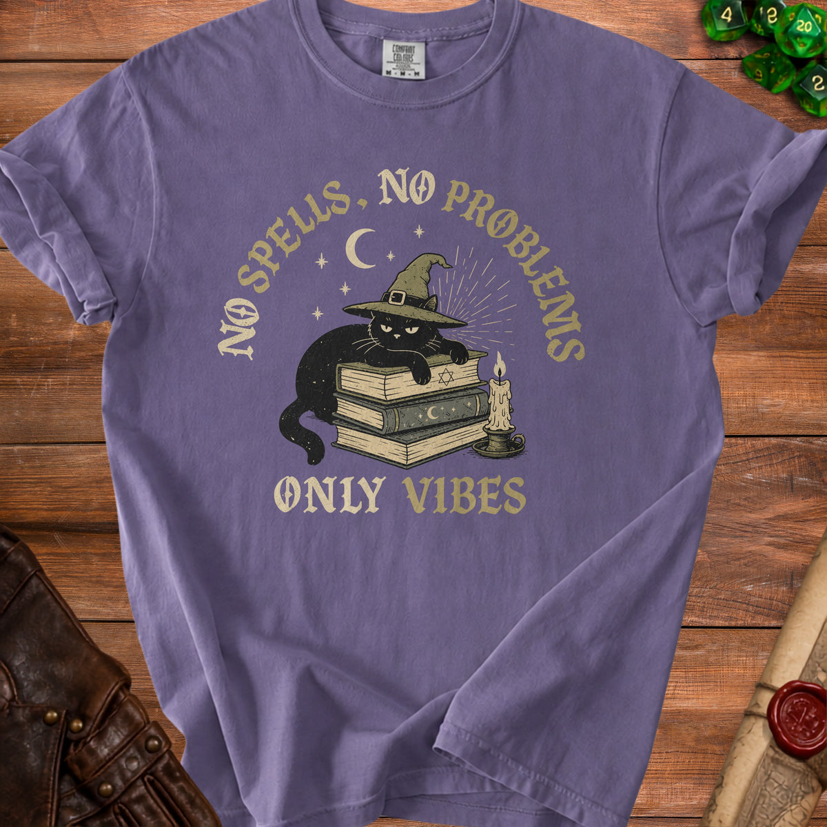 Purple t-shirt with a black cat wearing a witch hat on books, text reads "NO SPELLS. NO PROBLEMS. ONLY VIBES."