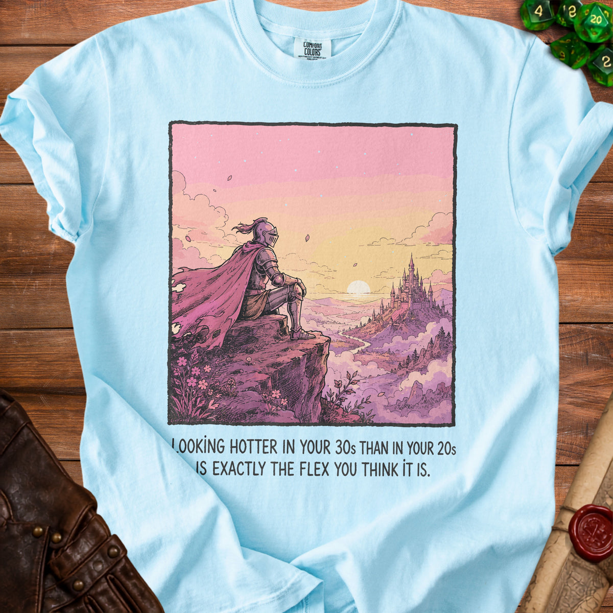 Light blue t-shirt with knight artwork and text: "Looking hotter in your 30s than in your 20s is exactly the flex you think it is."