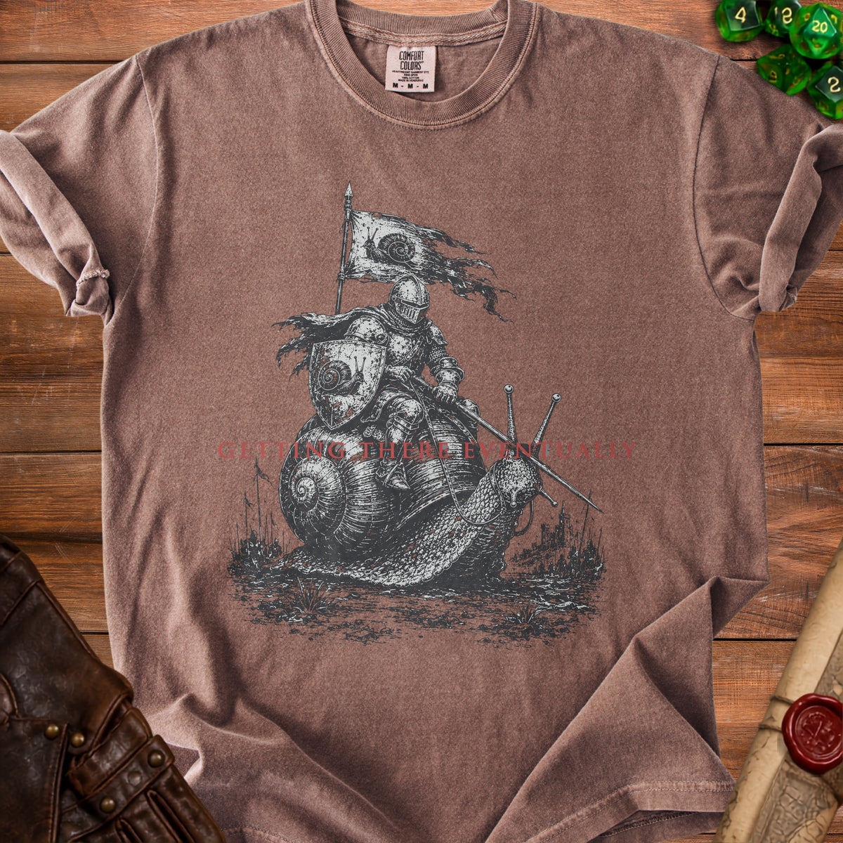 Knight riding snail with flag, text "GETTING THERE EVENTUALLY" on brown t-shirt.