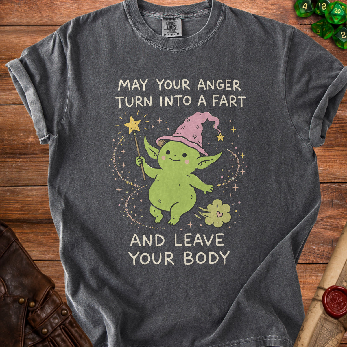 Dark grey t-shirt with green creature wearing a pink hat and text "MAY YOUR ANGER TURN INTO A FART AND LEAVE YOUR BODY".